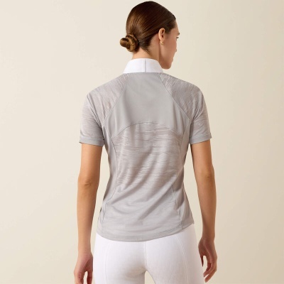 Perspectiva traseira de mulher com camisa cinza clara de manga curta e gola branca, e calças brancas justas.