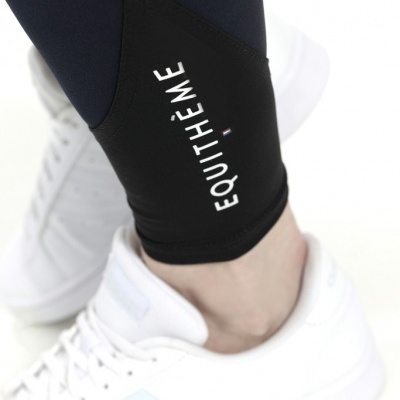 Calças desportivas pretas com texto 'EQUITHÈME' e sapatilhas brancas