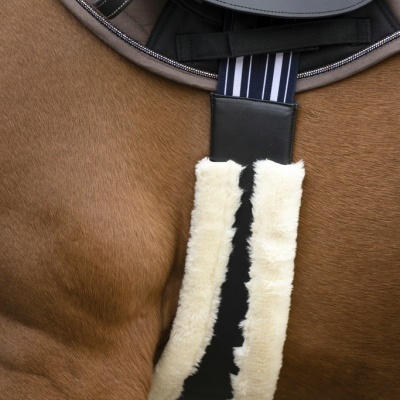 Cilha de sela em couro preto com pelo branco num cavalo castanho