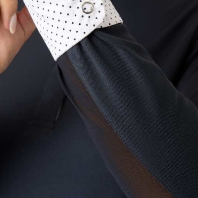 Manga de camisa escura com punho branco de pontos pretos e botões metálicos