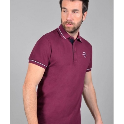 Homem a usar polo bordeaux com riscas brancas no colarinho e punhos e logótipo no peito, fundo cinzento