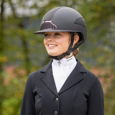 Jovem com capacete de equitação preto e casaco preto em ambiente exterior