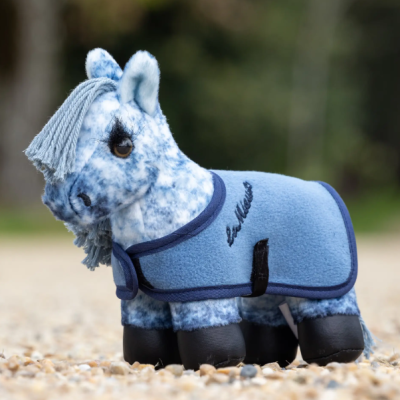 Pelúcia de cavalo azul com manta azul claro em superfície de pedras pequenas