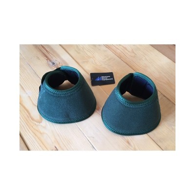 Protetores de cascos de cavalo verdes em chão de madeira com cartão