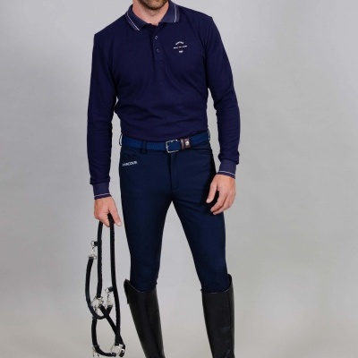 Homem com roupa de equitação azul escura e botas pretas segurando rédea