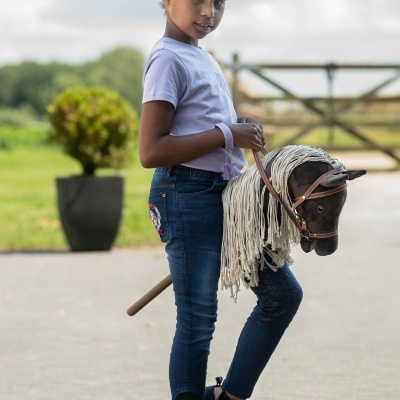 Menina segurando cavalo de brinquedo de pau com crina branca