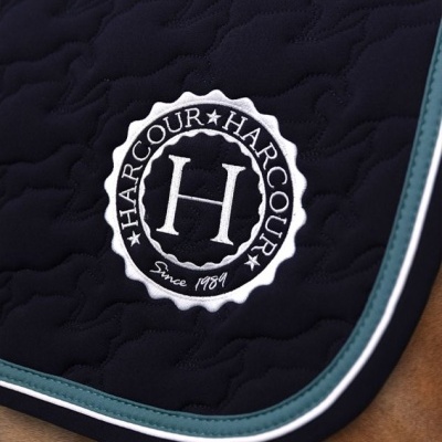 Tapete de sela azul escuro acolchoado com logo HARCOUR bordado sobre cavalo castanho