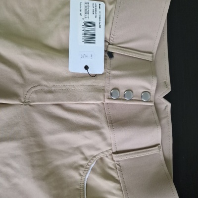 Calças bege com botões e etiqueta com código de barras