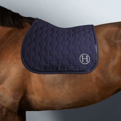 Manta de sela azul escuro com logotipo H sobre cavalo castanho