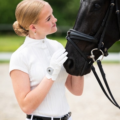 Mulher com roupa de equitação acariciando cavalo preto