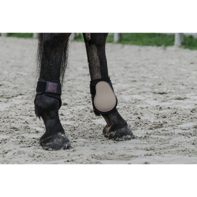 Patas dianteiras de cavalo com proteções e areia ao fundo