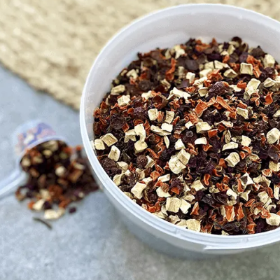 Recipiente branco com mistura seca de chá ou ervas coloridas em superfície cinza