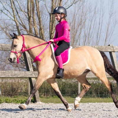 Menina a cavalo com roupa e equipamento de montaria em recinto de madeira