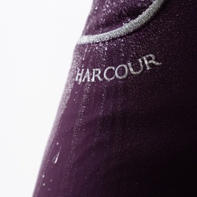 Detalhe de tecido roxo escuro com bordado HARCOUR e gotas de água