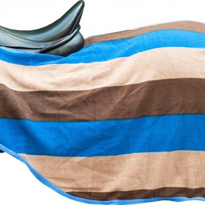 Cobertor para sela com riscas azuis, castanhas e bege sobre sela preta