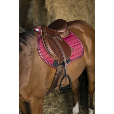 Sela de equitação em couro castanho escuro com mantilha rosa acolchoada numa cavalo castanho claro no celeiro