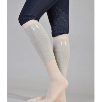 Meias compridas bege claro com letra H branca e calças azuis escuras.