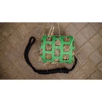 Brinquedo verde de plástico com corda preta e feno em tijoleira