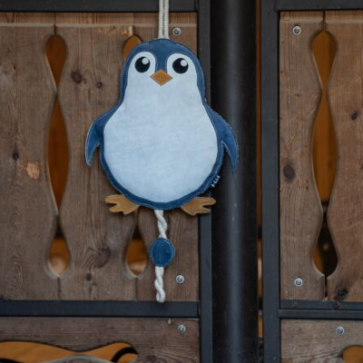 Brinquedo para cães em forma de pinguim pendurado numa vedação de madeira