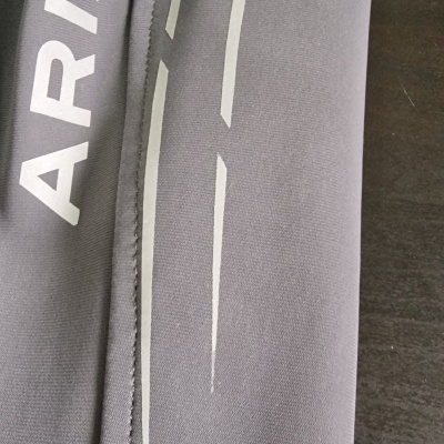 Peça de roupa cinza com texto ARIAT e padrão branco