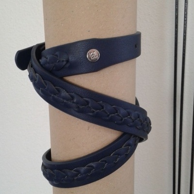 Cinto azul escuro em pele com padrão trançado enrolado em cilindro de cartão