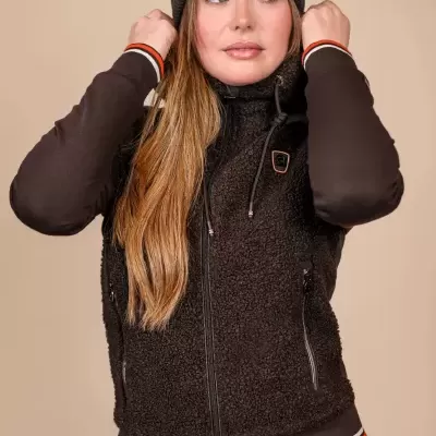 Mulher com colete de pelo preto, camisola de mangas compridas e gorro preto.