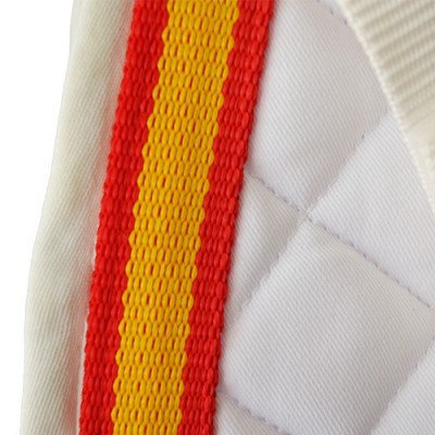 Faixa vermelha e amarela sobre tecido branco acolchoado com costura em losangos