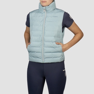 Colete azul claro acolchoado com fecho branco, usado por pessoa com t-shirt azul escura, fundo cinzento