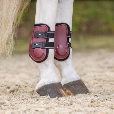 Protetores de casco vermelhos aplicados em patas de cavalo branco na areia