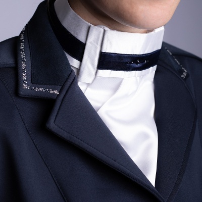 Casaco azul com detalhes brilhantes e camisa branca com gola alta e faixa preta em veludo