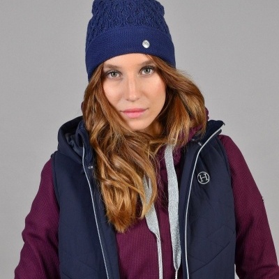 Mulher com roupas de inverno incluindo gorro azul e colete acolchoado azul.
