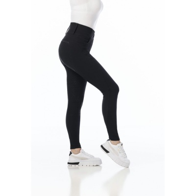 Mulher a usar calças legging pretas justas com camiseta branca e ténis brancos.