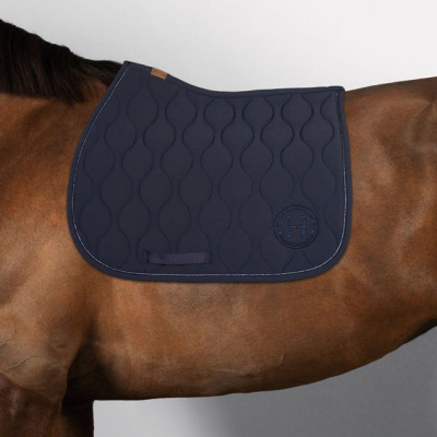Manta de sela azul escura acolchoada com padrão ondulado sobre dorso de cavalo castanho