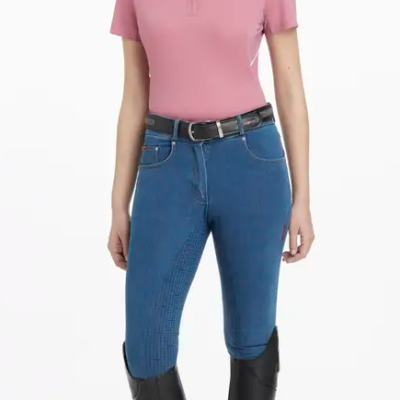 Mulher com polo rosa, calças de equitação azuis e botas pretas