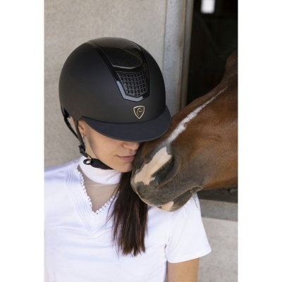 Capacete de equitação preto usado por mulher perto de cavalo castanho