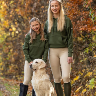 Mulheres com roupa verde e bege e cão golden retriever ao ar livre em floresta outonal.