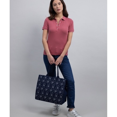 Mulher com polo rosa, jeans e bolsa azul escura com padrão floral