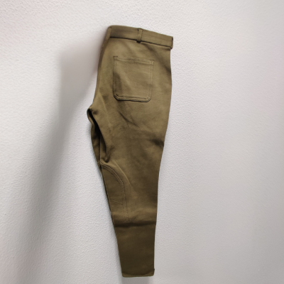 Calças caqui com bolso traseiro penduradas numa parede branca