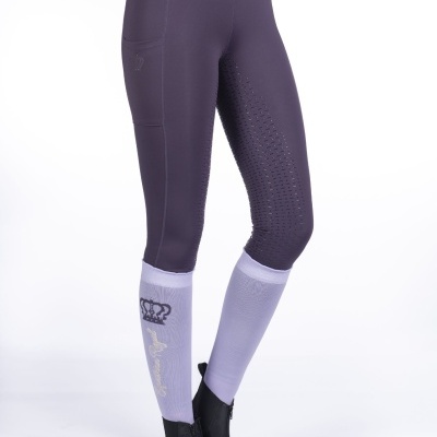 Leggings desportivas roxas com bolso lateral e polainas brancas com desenho de coroa e texto, calçado com botas pretas