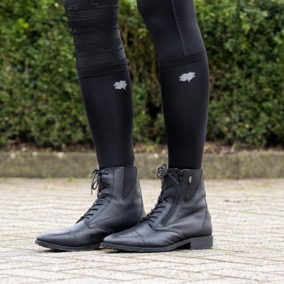 Botas pretas de couro com atacadores e fecho lateral em piso exterior de pedra