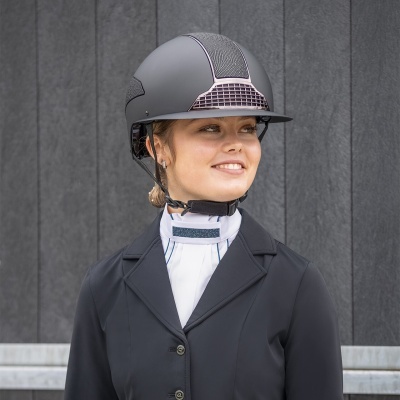 Mulher a usar capacete de equitação cinza com detalhe rosa, casaco preto e camisa branca