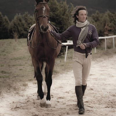Homem com roupa de equitação a conduzir um cavalo castanho