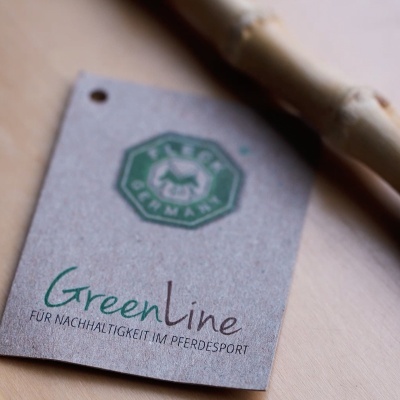 Etiqueta de cartão castanho com texto e logótipo verde junto a objeto de bambu sobre superfície de madeira