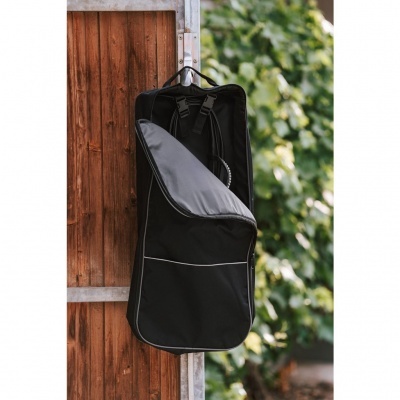 Mochila preta aberta pendurada numa porta de madeira com fundo de folhas verdes