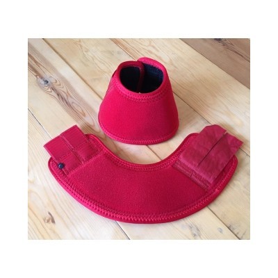 Conjunto de proteções vermelhas para cascos de cavalo sobre chão de madeira clara