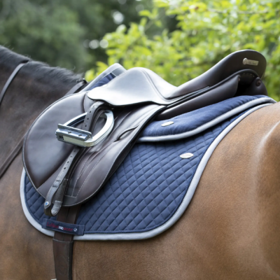 Sela de cavalo castanha com manta azul acolchoada e estribos metálicos