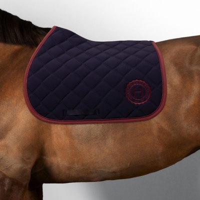 Tapete de sela acolchoado azul escuro com rebordo grená e logótipo H vermelho em cavalo castanho