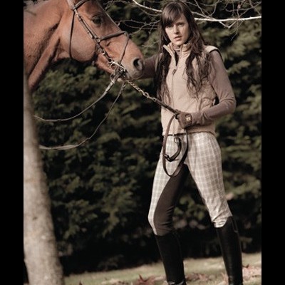 Mulher com roupa de equitação e cavalo castanho ao ar livre