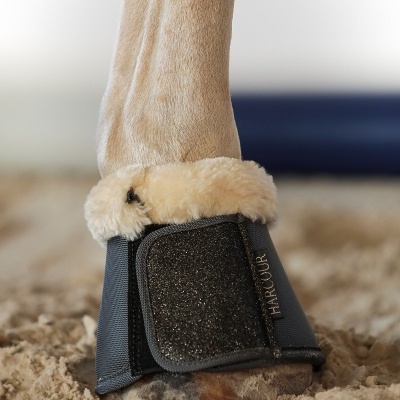 Proteção preta para casco de cavalo com pelo sintético bege e a palavra HARCOUR