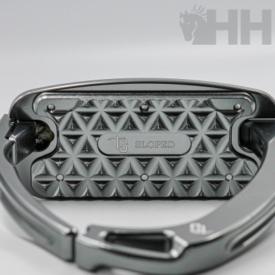 Mosquetão metálico cinza com textura triangular e texto TS SLOPED